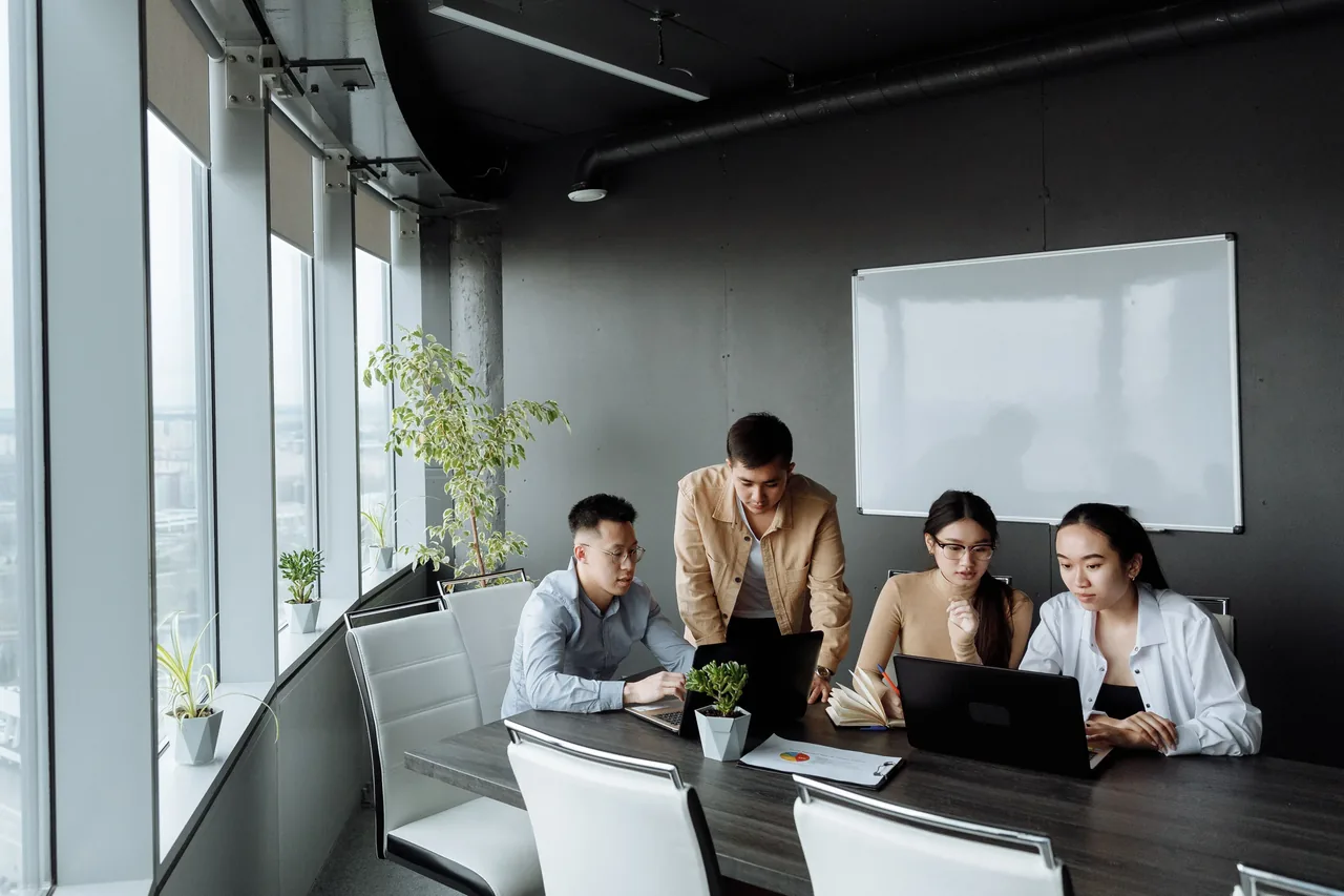 Gruppo di lavoro consulta documenti e computer in una sala riunioni