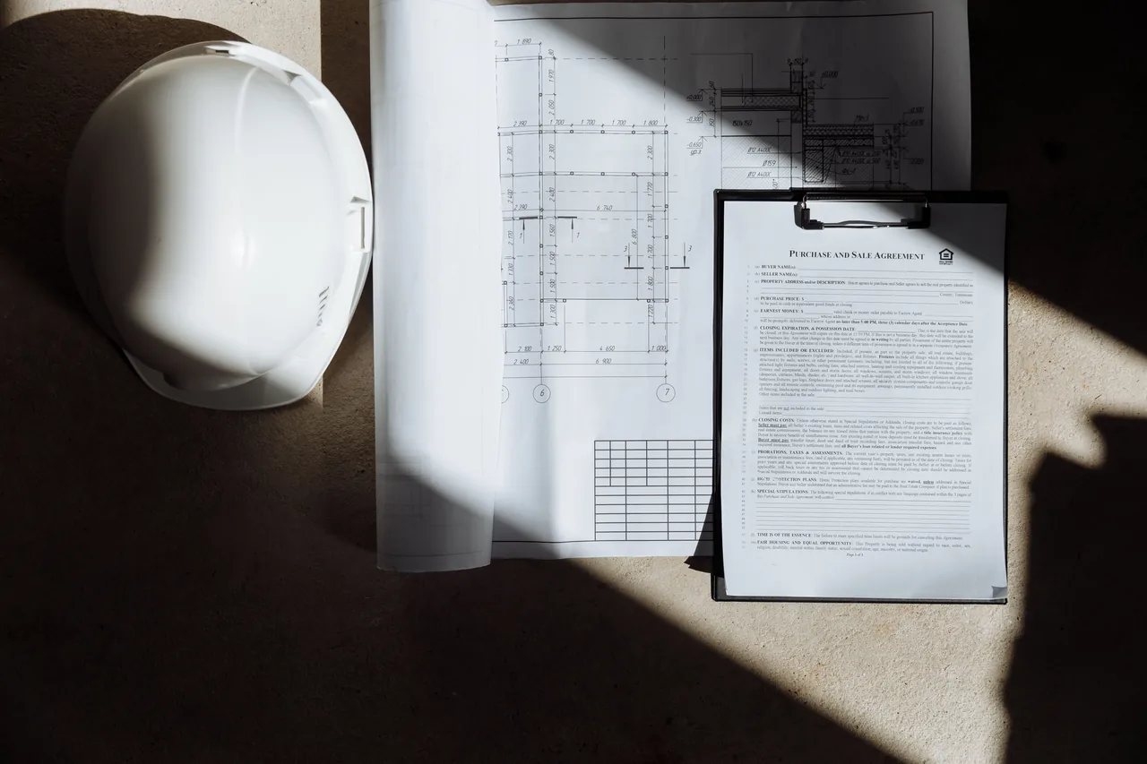 Casco da cantiere, planimetrie e documenti su un tavolo